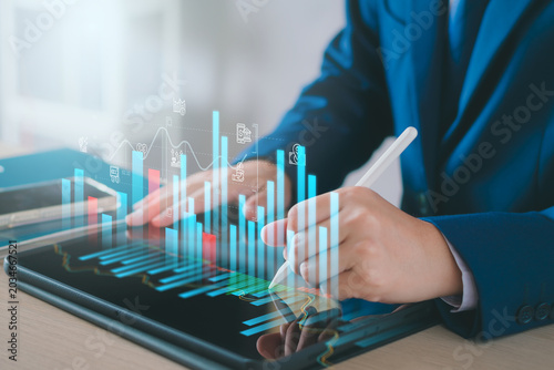 Businessman analyzing business investment data on a digital tablet with a stylus. financial bar charts, growth statistics, and economic indicators for corporate planning and market research concepts.