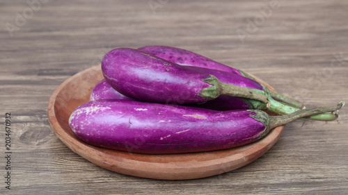 Photos fresh raw healthy eggplants or aubergine vegetable on wooden plate