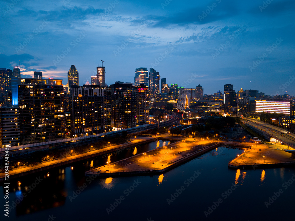 Fototapeta premium Montreal skyline illuminated at dusk and reflected in the water, Quebec, Canada.