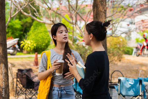 Obraz na plátně Two Asian students talking together during going classroom