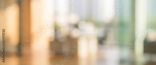 A blurred interior of a modern office space with sunlight streaming through large windows, showcasing a warm and inviting atmosphere.