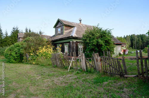 A street in a village in the Yaroslavl region of Russia with a fragment of an old traditional wooden house at sunset