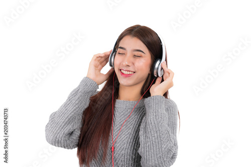 Smiling asian woman using headphones in studio with joyful smile and calm pose listening to audio