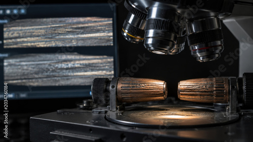 Forensic comparison microscopy of bullet striation for ballistic identification reveals highly tense analytical environment within dark crime lab displaying critical physical evidence