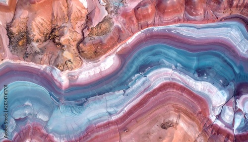 Aerial view of layered geological formations with vibrant hues, creating abstract patterns