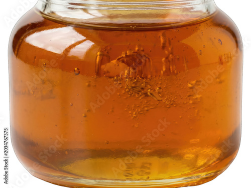 Golden amber honey dripping from glass jar on transparent background