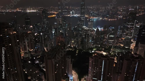 Cinematic aerial view of illuminated corporate towers in Hong Kong after dark.