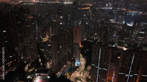 Wide drone shot panning across Hong Kong downtown and bay area at night.