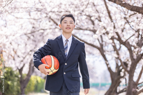 桜並木を歩くバスケットボール部の男子学生