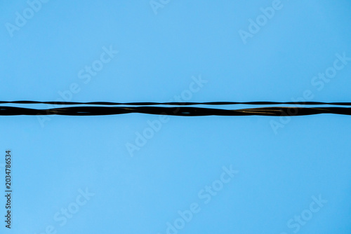 Obraz na plátne Utility cables stretching horizontally across a clear, bright blue sky