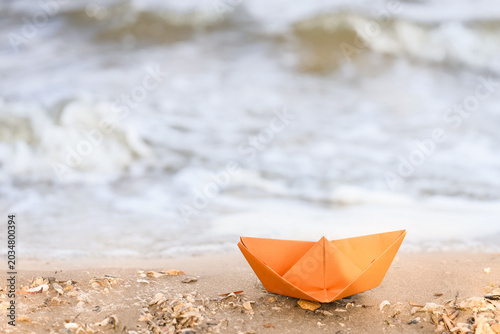 Orange paper boat on shore ...