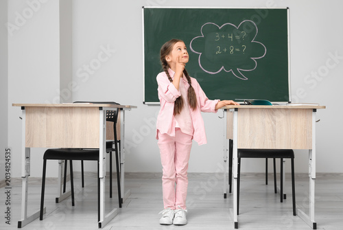 Tableau sur toile Thoughtful little schoolgirl having Math lesson in classroom