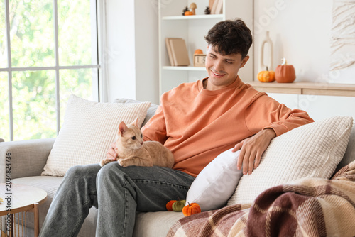Young man with cute cat sit...