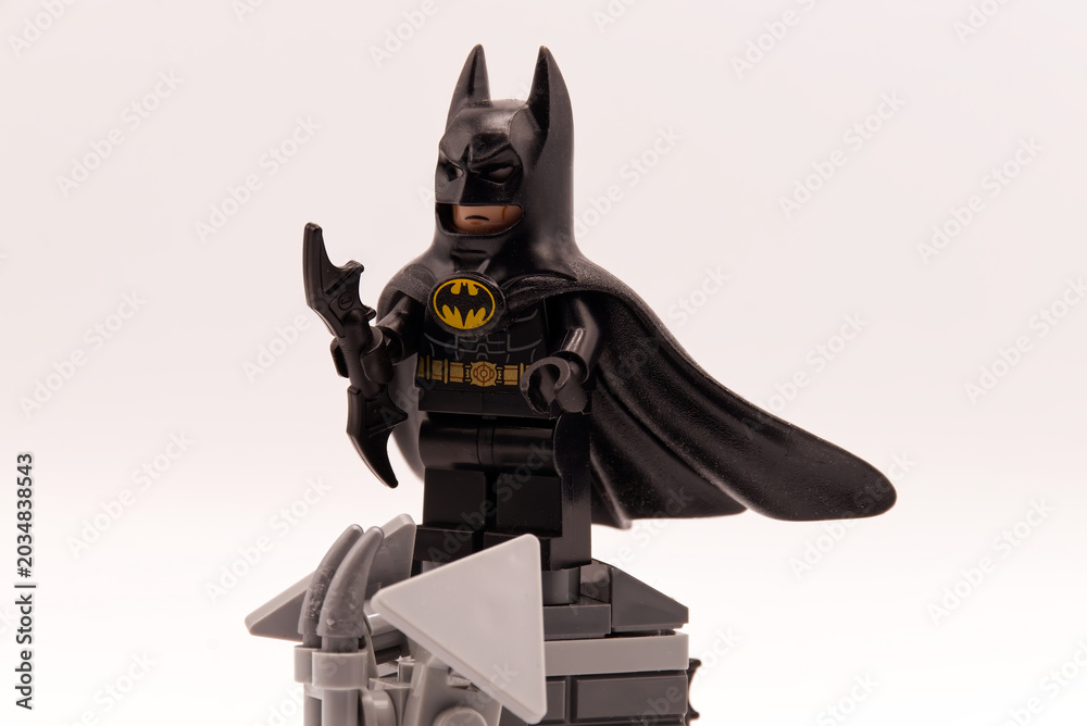 Obraz premium Bologna - Italy - April 2026: Batman lego minifigure standing on a grey brick pedestal holding a batarang weapon against a plain white background.