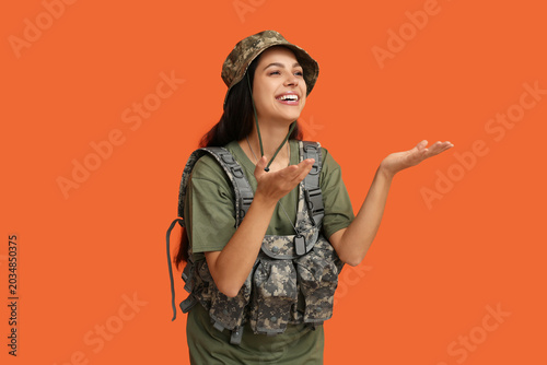 Beautiful young female soldier laughing on orange background
