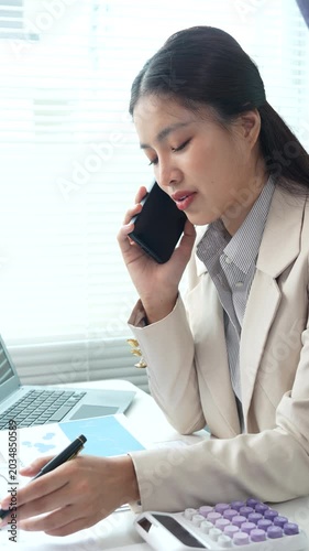 Young businesswoman reviewing financial documents and reports at a modern office desk, analyzing data and managing paperwork with focus and professionalism.