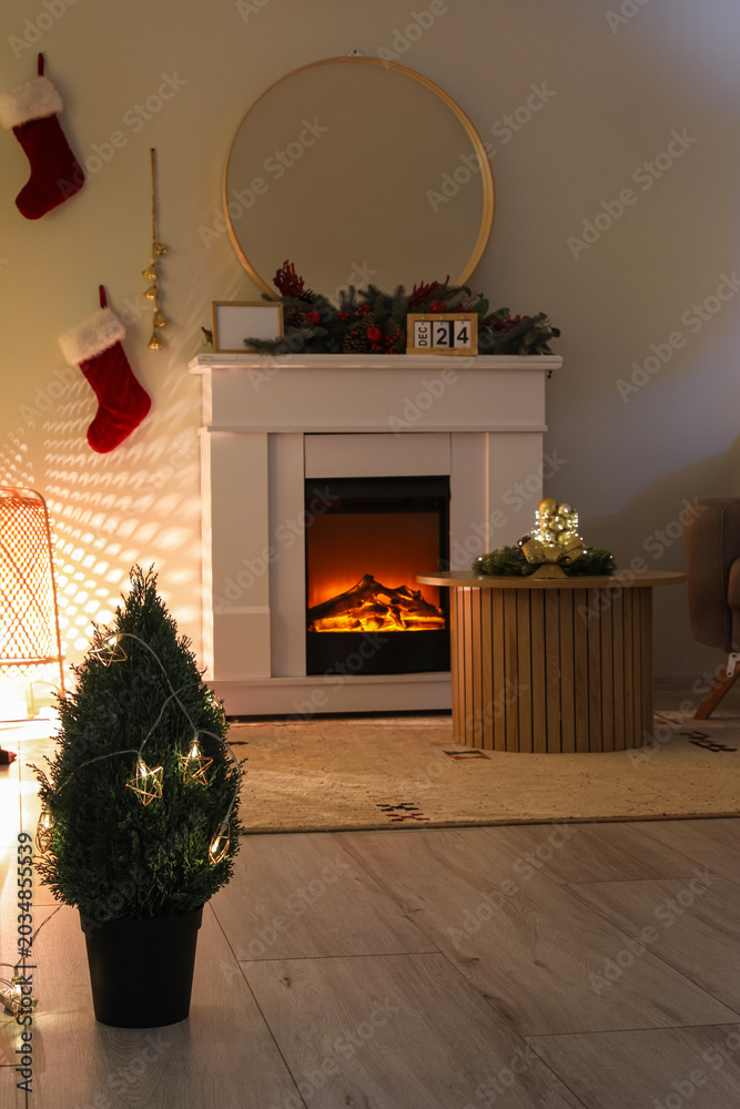 Fototapeta premium Fireplace with Christmas decorations and glowing lamp in dark living room
