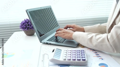 Business professional reviewing financial reports and performance charts at a modern office desk, analyzing data, planning strategy, and managing corporate documentation.