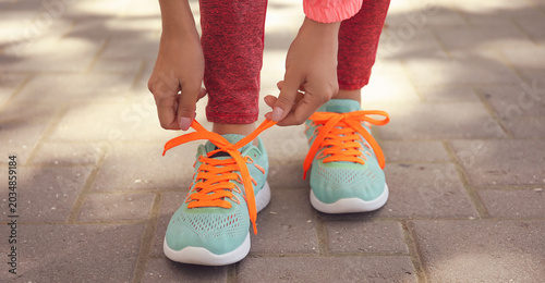 Konstfotografi Young woman tying shoe lace outdoors