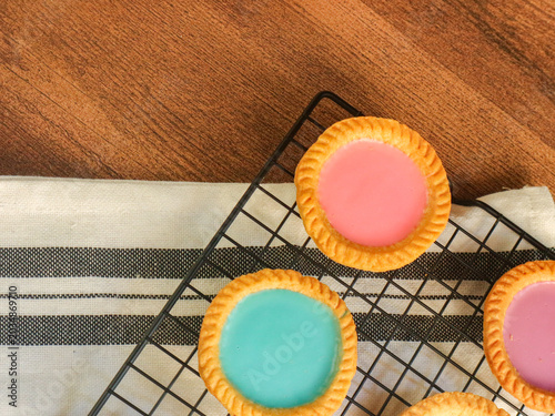 Slika na platnu Colorful Iced Tartlets on Wire Rack in Rustic Kitchen