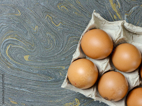 Fresh Brown Eggs in Cardboard Egg Carton on Marbled Gray Surface