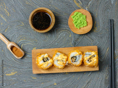 Golden Sushi Rolls with Sauce on Wooden Board in Rustic Setting