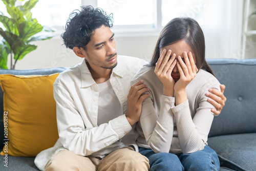 Anxiety depress, grief asian young couple comfort discuss concern encourage empathy and support, worry about problem mental health about relationship after marriage, upset wowan sad on sofa at home.