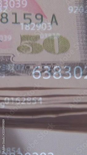 Vertical video: On scan, camera panning over stacked 50s, numbers floating to reveal serials