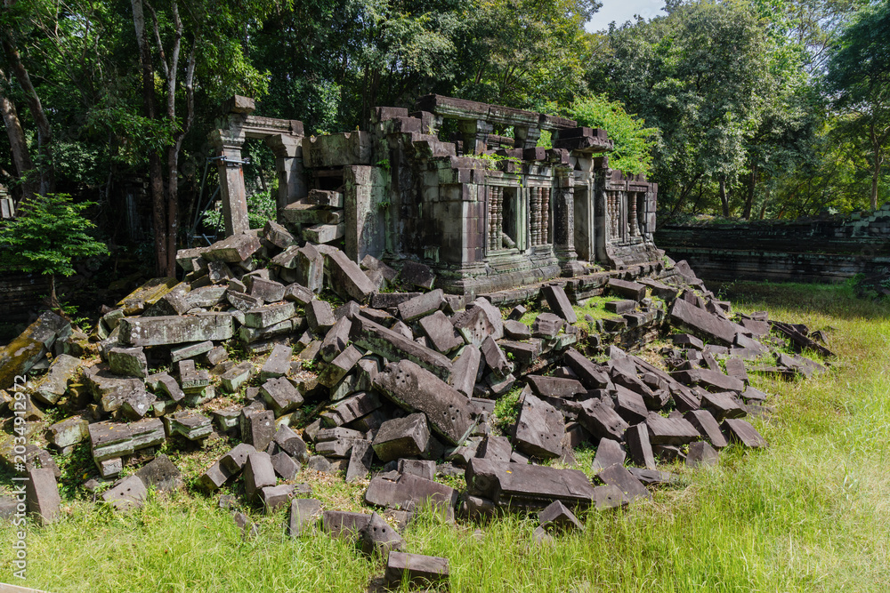 Fototapeta premium The ancient ruins of Beng Mealea temple in Cambodia, near Siem Reap, lie in disarray, with large stone blocks scattered across the overgrown grounds, showcasing the passage of time