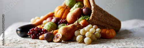 Cornucopia overflowing with fruits and vegetables on a textured surface  