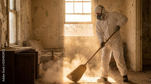 Hazmat Worker Cleaning Dust in Abandoned Building Wearing Protective Suit and Respirator