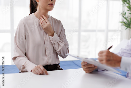 фотографія Female patient experiencing sore throat or neck pain, consulting with doctor, de