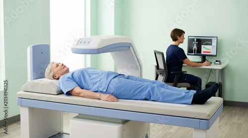 Senior woman undergoing bone density scan in clinic. Female patient getting osteoporosis screening with medical imaging machine. Healthcare and diagnostic concept