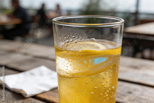 Glass of sparkling lemon water on wooden table with blurred background