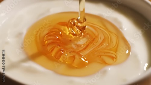 Golden Honey Pouring into a White Bowl, Delicious Sweet Food Concept.