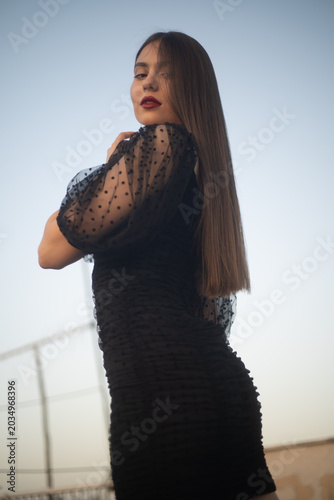 Beautiful and sensual young woman in a dress on a building rooftop in the golden hour