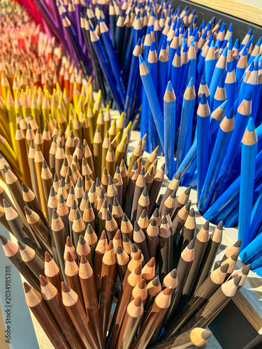 Many colored pencils with sharpened tips are neatly organized by hue, creating a vibrant display of browns, yellows, and blues, symbolizing creativity, art, and education - stock photo
