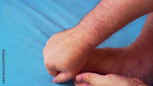 Aesthetic Men's Body Care Close-Up. A minimalist close-up shot focusing on male hands massaging a foot in gentle, natural daylight. 