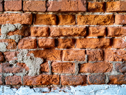 Texture of a collapsing red brick wall. Close-up. Copy space. Old red stone background.