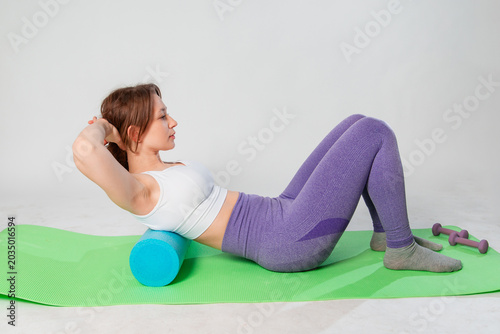 Full length portrait of young woman in sportswear doing abdominal exercise on yoga mat isolated on white background.