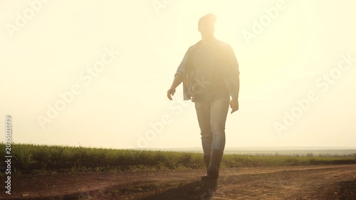 Man walking down dirt road. Silhouette of farmer walking in a field. Farmer working on a field lifestyle in evening. A individual strolling along a unpaved path.