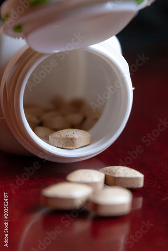 Pills spilling out of a bottle isolated on dark background, Vitamin for health