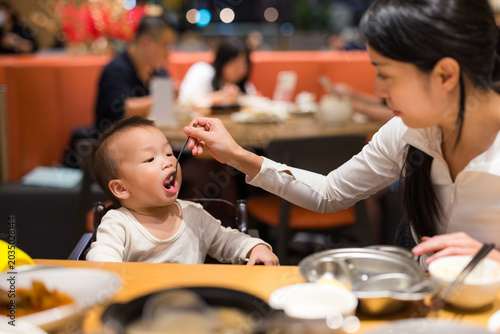 Mother feeding her son with a spoon in a restaurant