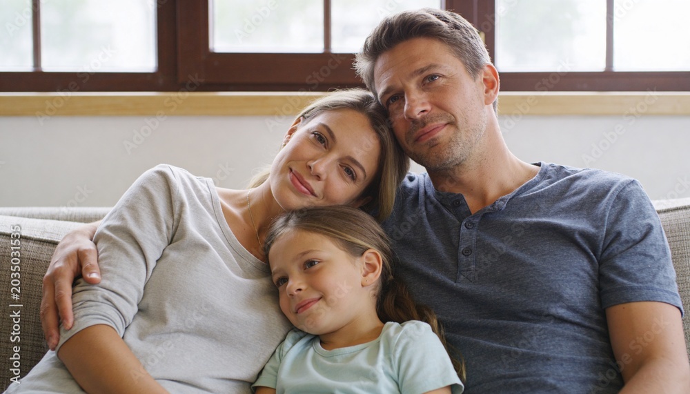 Obraz premium Sitting family cuddling daughter on sofa under wood-framed window, wearing henley and mint t-shirt