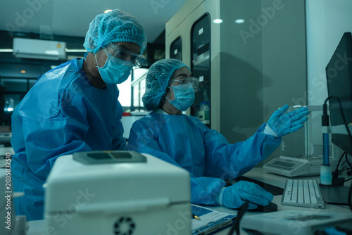 Medical or research scientist or doctor using looking at a test tube of clear solution in a lab or laboratory.