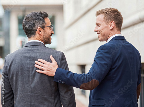 Obraz na plátne Two professional male colleagues sharing a moment of encouragement and understanding in a formal urban business setting