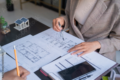 Asian female engineers planning solar energy project using blueprints for renewable energy development