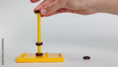 Photography Close up of hand demonstrating magnetic repulsion with ring magnets on stand