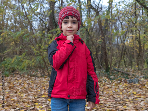 Thoughtful Little Boy in Autumn Forest Holding Hand Near Chin