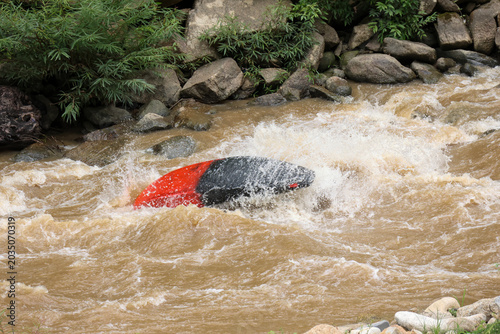Bilde på lerret Red black car submerged flooded raging muddy river raging water emergency danger